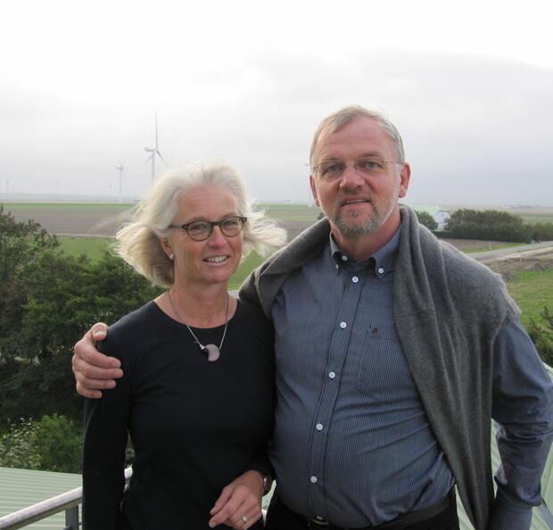 Dirk und Thoma Ketelsen stehen Arm in Arm auf einem Balkon, im Hintergrund die neblige nordfriesische Landschaft.